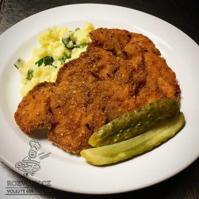 Smažený kuřecí řízek v pikantním kabátku, šťouchaný brambor, kyselá okurka